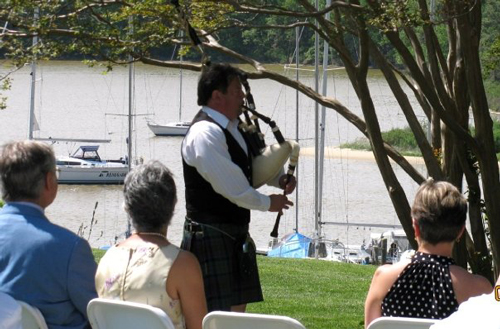 Tim Carey playing his bagpipe by a river at a wedding