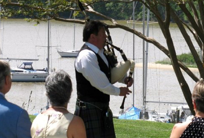 Tim Carey playing his bagpipe by a river at a wedding
